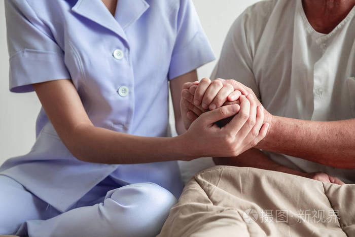 安慰的手.年轻的护士握着老人的手.