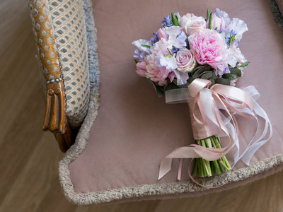 特写照片的美丽的婚礼花束与柔和的粉红色和紫色的花朵复古扶手椅背景