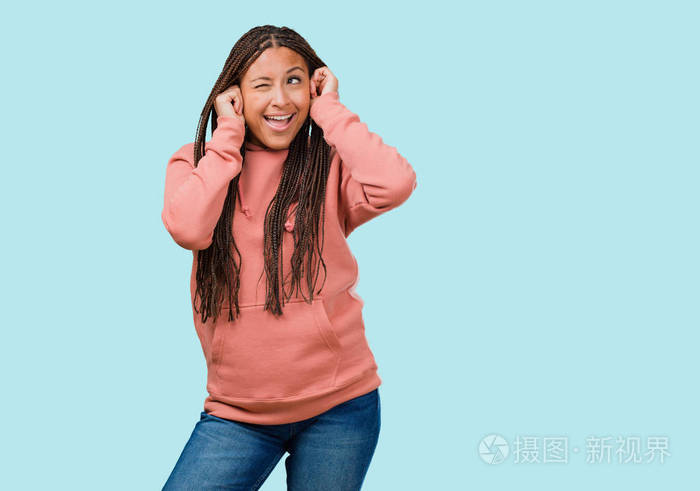 一个年轻的黑人妇女的肖像戴着辫子捂着耳朵用手, 愤怒和厌倦听到一些声音
