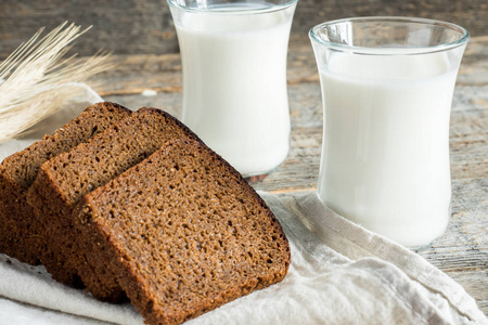 新鲜健康的牛奶在玻璃杯和切片谷物面包在一个木制的乡村背景