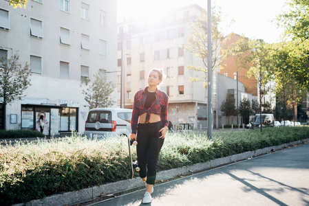 年轻女子行走户外抱滑板