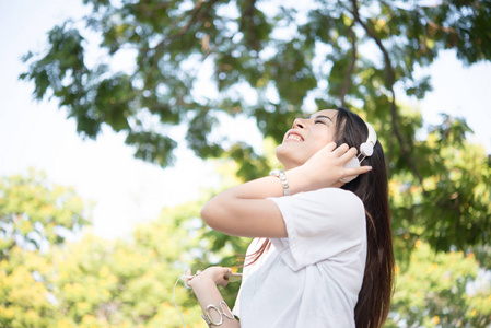 一个微笑的女孩的肖像听音乐, 而放松自然公园户外