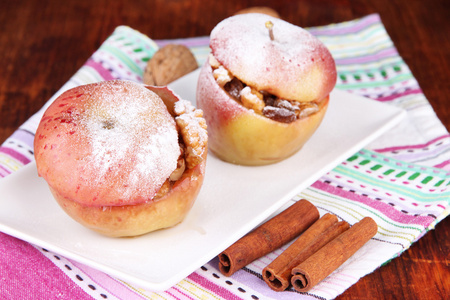 坚果和葡萄干在木制的背景上的餐巾纸上烤的苹果