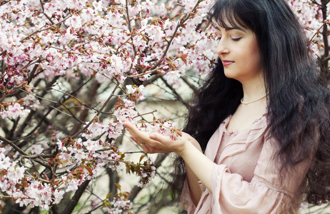 黑发女人在春天花朵的花园