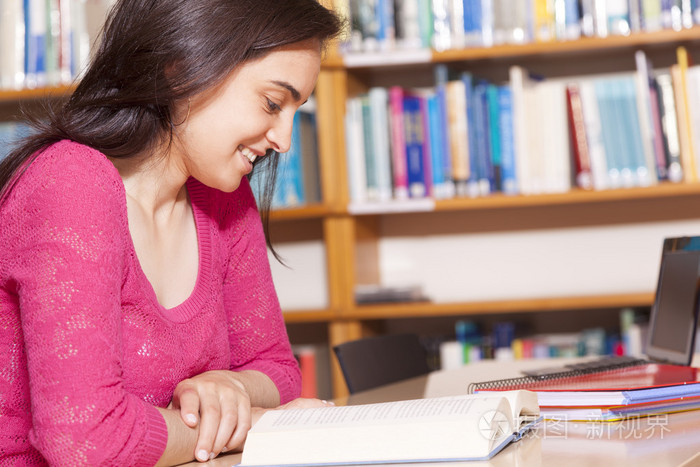 面带笑容的女学生在图书馆读书