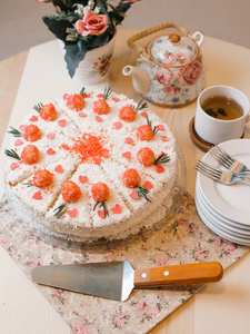 观赏海绵蛋糕与油 , 浆果馅 , 椰子薯片和装饰甜花在顶部服务与茶具 , 叉子 , 花束和花餐巾