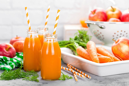 新鲜胡萝卜和苹果汁的白色背景。胡萝卜和苹果汁在玻璃瓶的白色桌上。白底苹果胡萝卜汁