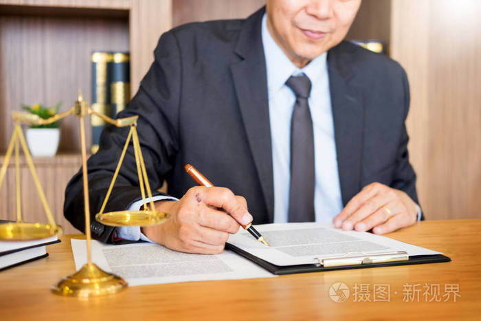 律师法官在法庭的办公桌上阅读文件工作在木制办公桌的背景木槌金色的