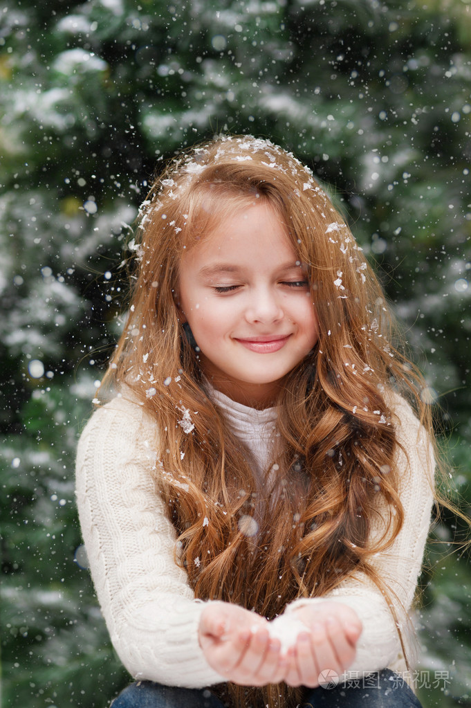 漂亮的小女孩捉住雪花