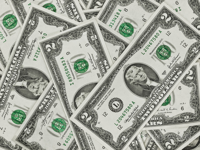 一堆的两个美元的钞票作为钱背景