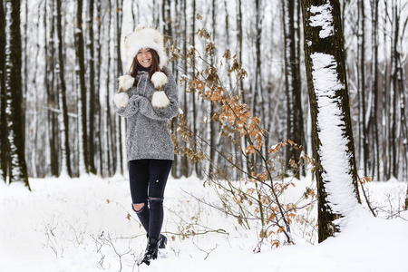 美丽的年轻妇女在森林里享受冬天
