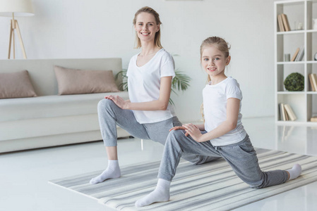 快乐的母亲和女儿热身前锻炼瑜伽垫