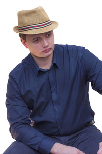 年轻的白种人种族男子纵向蓝色衬衫和夏季帽子坐在一旁看白色背景