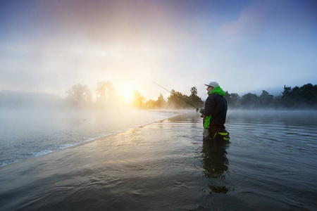 渔夫手持钓竿, 站在河边。美丽的日出之光。户外活动和花费利热时间
