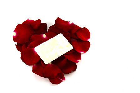 红色的玫瑰花瓣，在一个心的形状和孤立在白色的老卡