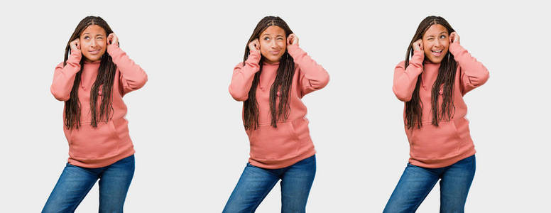 一套健身年轻的黑色妇女覆盖耳朵与手在灰色背景