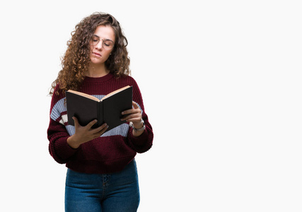 年轻的黑发女孩在孤立的背景上戴着眼镜看书, 在聪明的脸上自信地表达着思考的严肃