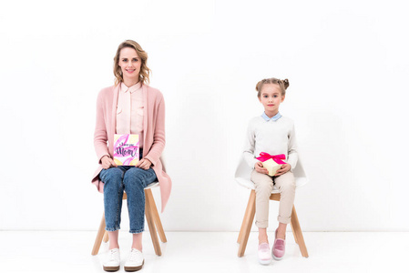 母亲和女儿坐在椅子上明信片和花束, 母亲节快乐的概念