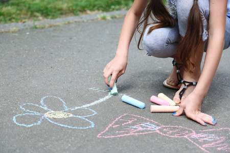 在沥青上用粉笔绘制的可爱的小女孩