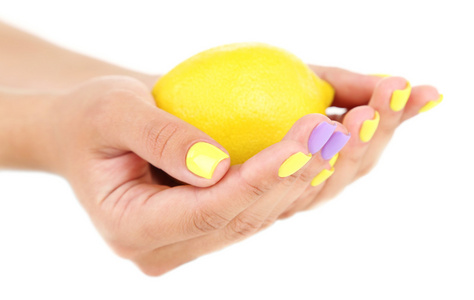 抱着新鲜的柠檬，孤立的白色衬底上的时尚多彩指甲的女性双手