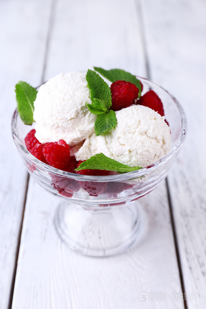 在玻璃碗里颜色木制背景板上覆盆子奶油冰淇淋