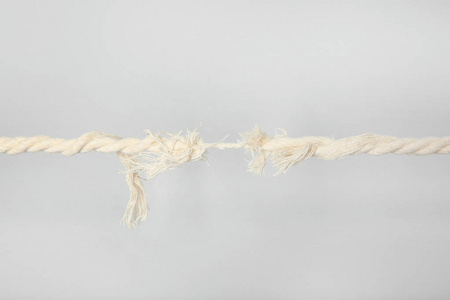 灰色背景下断裂点上的磨损绳索在白色背景的断裂点磨损的绳子胜利者和
