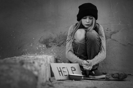 无家可归的贫困少女坐在户外附近的空碗和一块纸板与 word 帮助