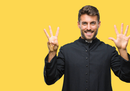 年轻的天主教基督教牧师男子在孤立的背景显示和指向八的手指, 而微笑着自信和快乐