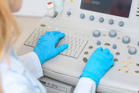 超声扫描仪在手套中的女性产科妇科医生的裁剪照片