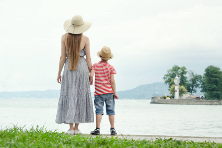 妈妈和儿子站在码头上。海在背景, 灯塔