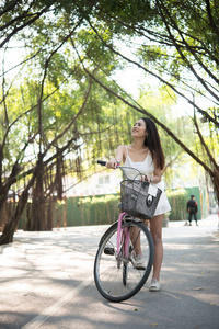 在公园里骑自行车的年轻漂亮的女人。在自然公园户外放松的妇女