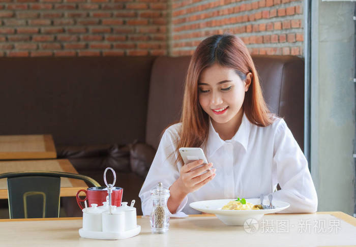 快乐的女人在餐厅吃午饭, 并呼吁智能手机照片-正版商用图片06z5z7