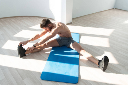 在一间健身房和肌肉伸缩肌肉运动健美健身模型在地板伸展肌肉男