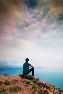 一个孤独的年轻人坐在一座小山照片