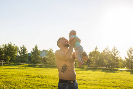 快乐的父亲抱着小儿子, 把婴儿扔进了空中。幸福家庭父亲节和孩子的概念