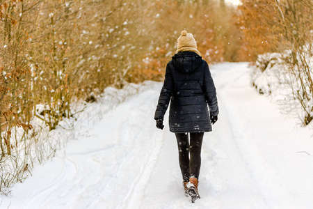 冬天的女人在雪地上散步, 女孩穿着黑色大衣在公园, 后景色