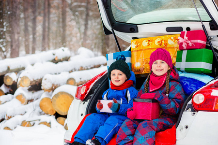 快乐的孩子们在车厢里享受着许多圣诞礼物。寒冷的冬天, 下雪的天气