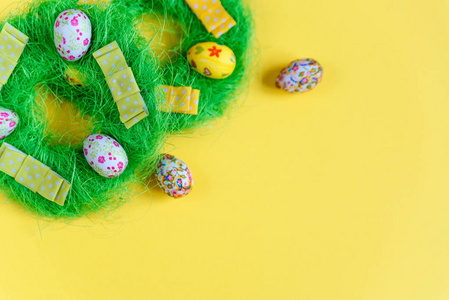 绿色装饰复活节花圈与小彩色复活节彩蛋黄色背景