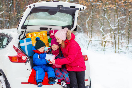快乐的孩子们在车厢里享受着许多圣诞礼物。寒冷的冬天, 下雪的天气