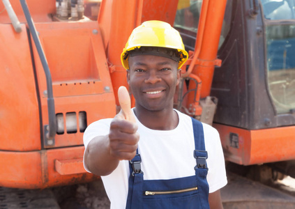 非洲建筑工人用红色挖掘机在建筑工地展示拇指