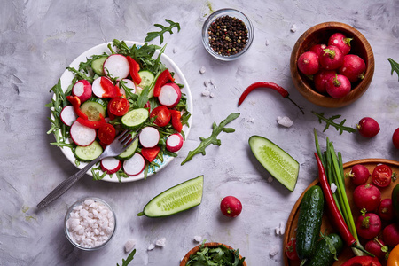 创意新鲜蔬菜沙拉与 ruccola, 黄瓜, 西红柿和 raddish 在白色板材, 选择性重点