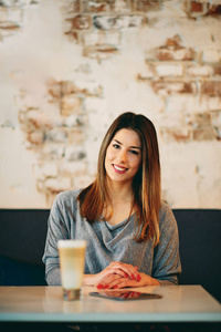 年轻的白种女人坐在咖啡馆喝咖啡时使用片剂