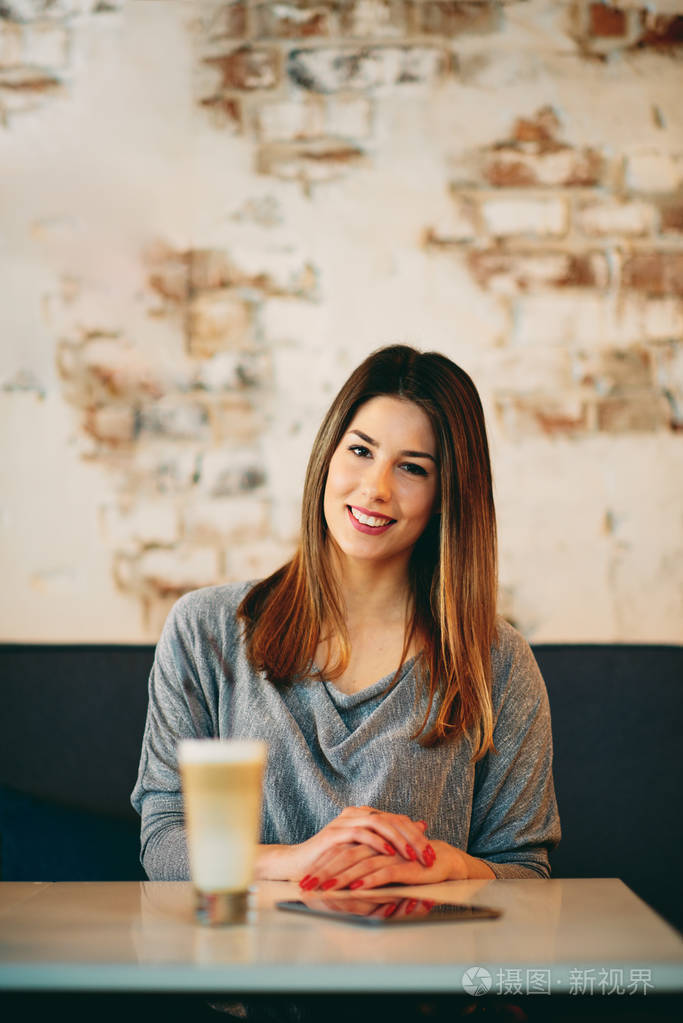 年轻的白种女人坐在咖啡馆喝咖啡时使用片剂