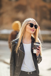 年轻漂亮的女孩走在街上, 她的咖啡杯的 h。