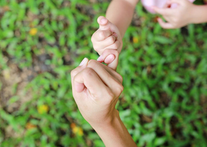 母亲和女儿在绿草花园做一个小指承诺