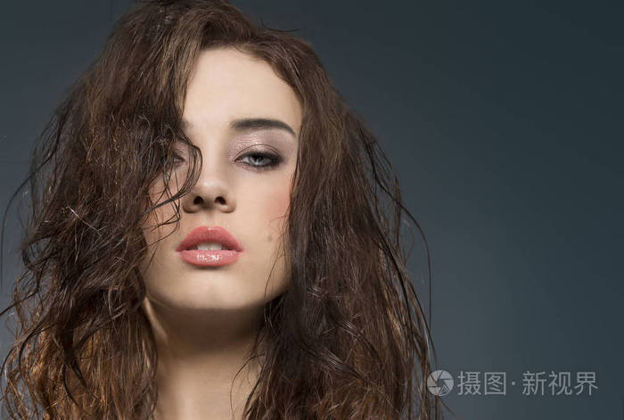性感的肖像特写一个年轻美丽的女孩与湿头发在灰色背景