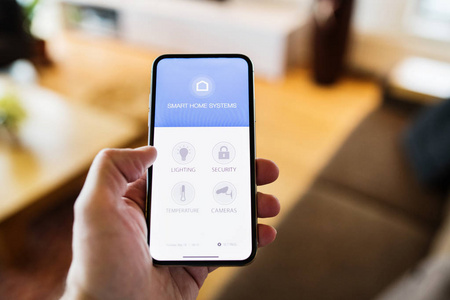 一个拿着智能手机和智能家庭屏幕的女人。