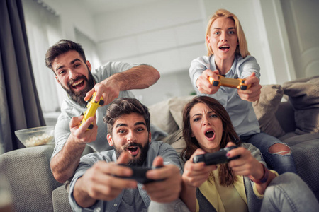 视频控制台年轻的朋友在沙发上玩视频游戏控制台照片