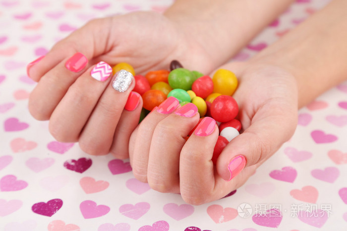 时尚多彩的女性手钉着五颜六色的糖果,在明亮的背景上