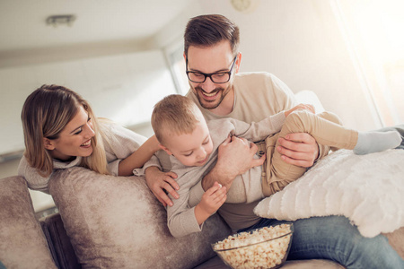 快乐的年轻家庭看电视和吃爆米花